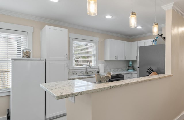kitchen with freestanding refrigerator, white cabinets, crown molding, light stone counters, and hanging light fixtures