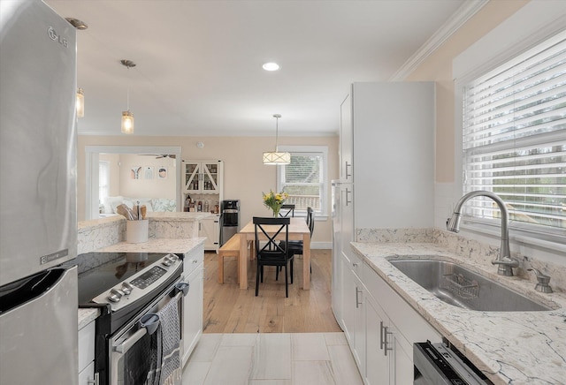 kitchen featuring appliances with stainless steel finishes, a sink, crown molding, hanging light fixtures, and white cabinetry