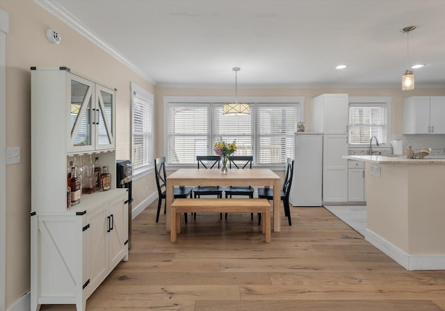 dining space with ornamental molding, light wood finished floors, baseboards, and recessed lighting