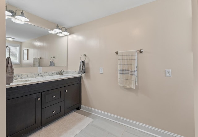 bathroom featuring baseboards, tile patterned floors, and double vanity