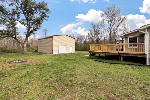 view of grassy yard featuring a detached garage, a wooden deck, and an outdoor structure