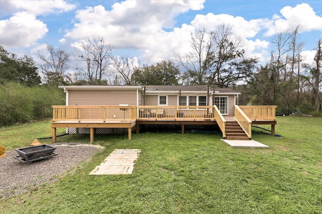 rear view of property with a fire pit, a yard, and a deck