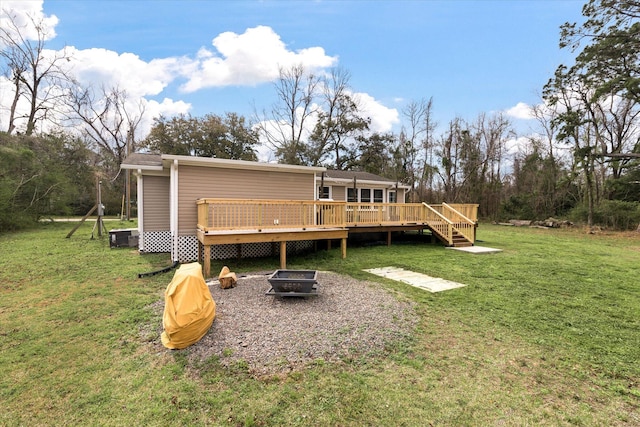 back of house featuring a fire pit, a deck, and a yard