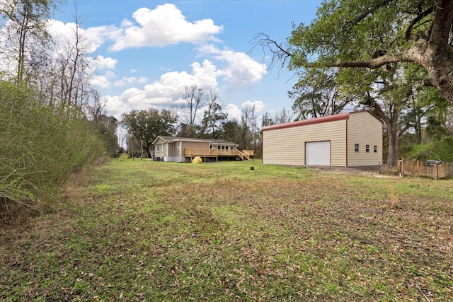 view of grassy yard featuring a deck, an outdoor structure, and a garage