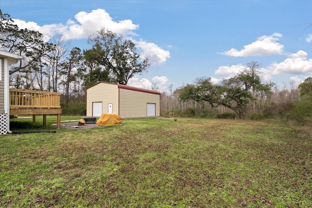 view of green lawn featuring a detached garage, a deck, and an outdoor structure