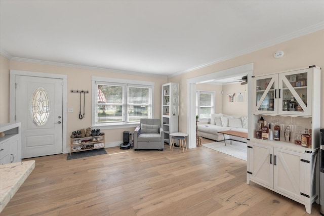 foyer entrance with ornamental molding, light wood finished floors, and a ceiling fan
