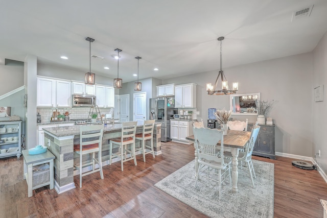 dining room with baseboards, visible vents, wood finished floors, an inviting chandelier, and recessed lighting