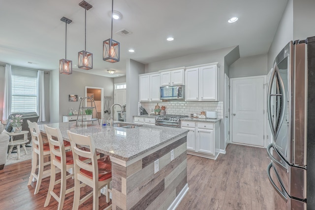 kitchen featuring a sink, white cabinetry, appliances with stainless steel finishes, light wood-type flooring, and decorative backsplash