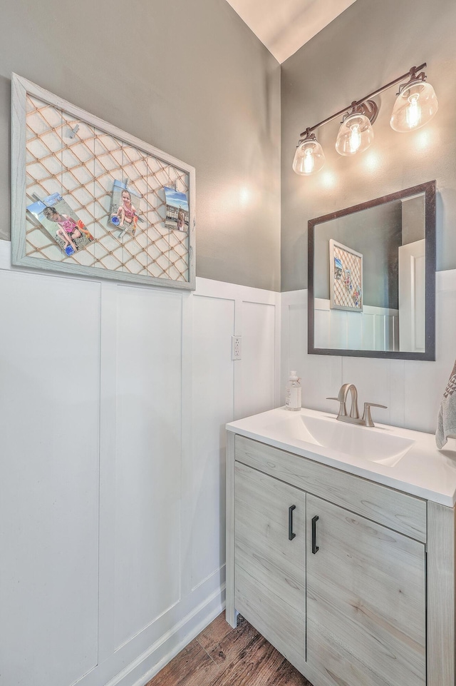 bathroom with a wainscoted wall, a decorative wall, wood finished floors, and vanity