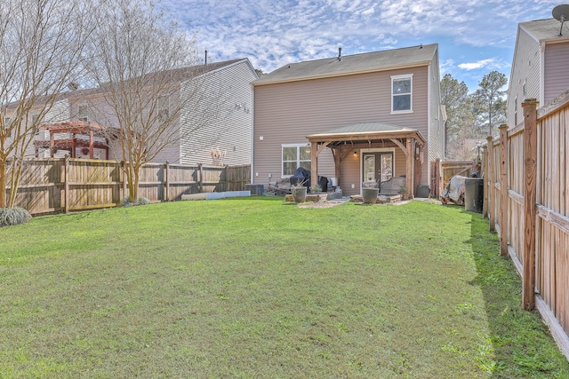 rear view of house featuring a gazebo, a yard, and a fenced backyard