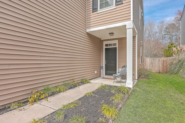 entrance to property featuring fence and a yard