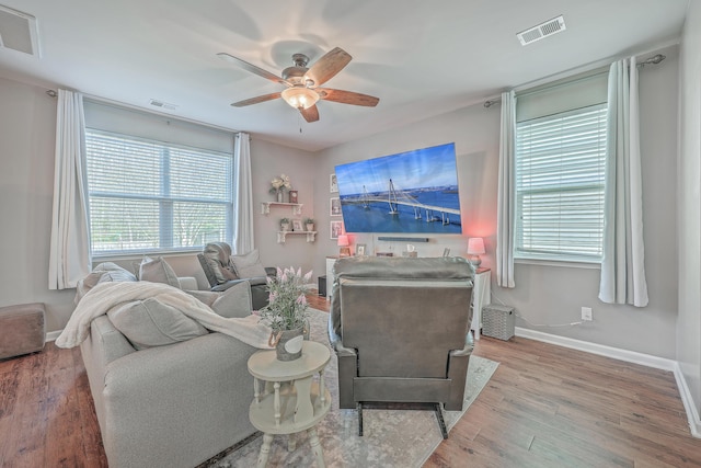 living area with ceiling fan, wood finished floors, and visible vents