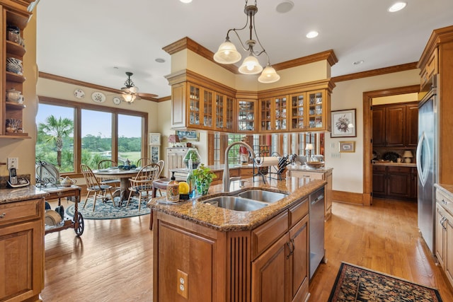 2834 Parkers Landing Rd, Mount Pleasant, SC 29466 - kitchen with brown cabinets, an island with sink, appliances with stainless steel finishes, light wood finished floors, and ornamental molding