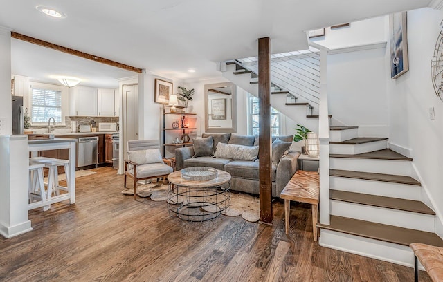 living room featuring crown molding, wood-type flooring, and sink