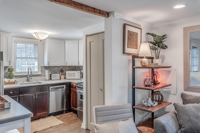 kitchen featuring sink, light wood-type flooring, ornamental molding, appliances with stainless steel finishes, and white cabinetry