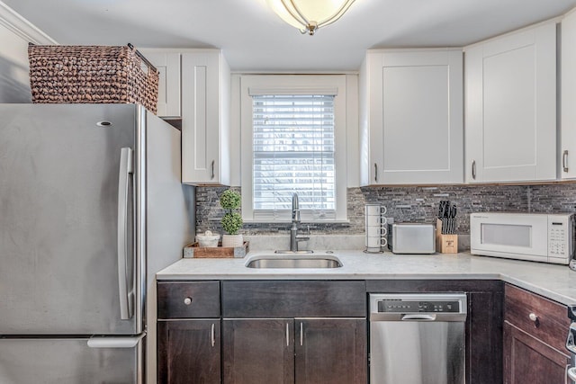 kitchen with backsplash, dark brown cabinets, stainless steel appliances, sink, and white cabinetry