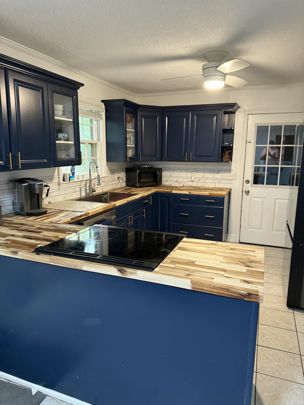 913 Natchez Trl, West Columbia, SC 29169 - kitchen with wooden counters, blue cabinets, a textured ceiling, backsplash, and stovetop with downdraft