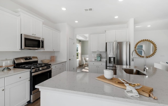 kitchen featuring stainless steel appliances, sink, white cabinets, and decorative backsplash