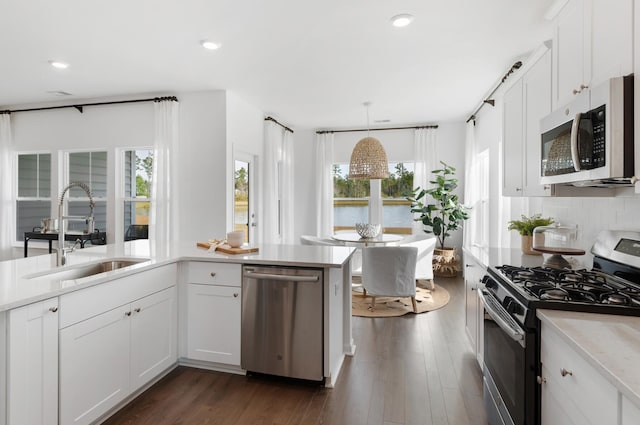 kitchen featuring stainless steel appliances, sink, hanging light fixtures, and white cabinets