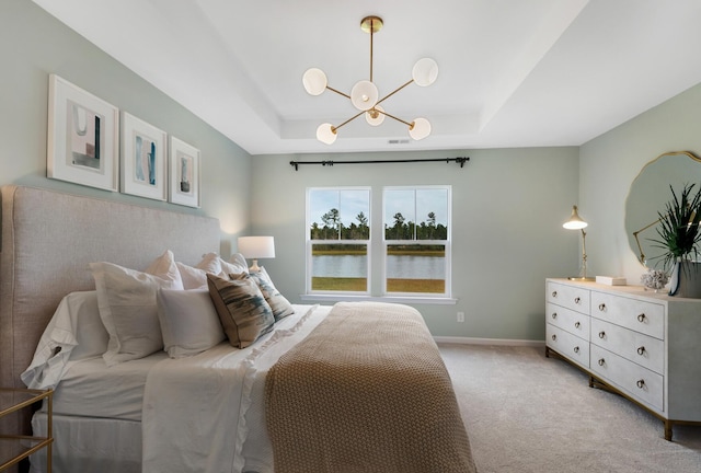 bedroom featuring a water view, light carpet, a chandelier, and a tray ceiling