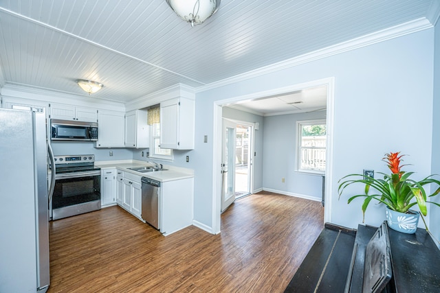 kitchen featuring appliances with stainless steel finishes, sink, white cabinets, ornamental molding, and dark hardwood / wood-style floors