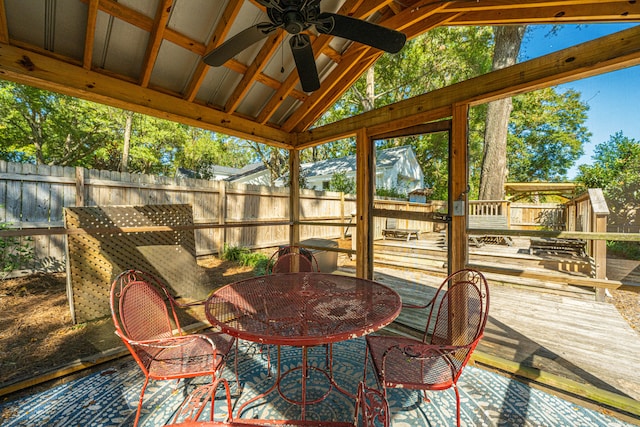 sunroom / solarium with ceiling fan and vaulted ceiling with beams