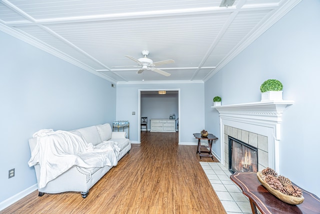 living room featuring ornamental molding, a tile fireplace, light wood-type flooring, and ceiling fan