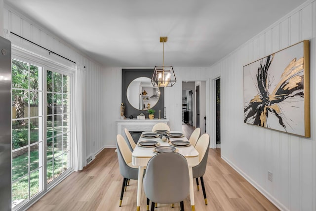 dining room with light wood-type flooring, a chandelier, crown molding, and baseboards