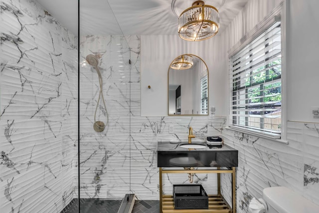 bathroom featuring tile walls, toilet, a chandelier, a marble finish shower, and vanity