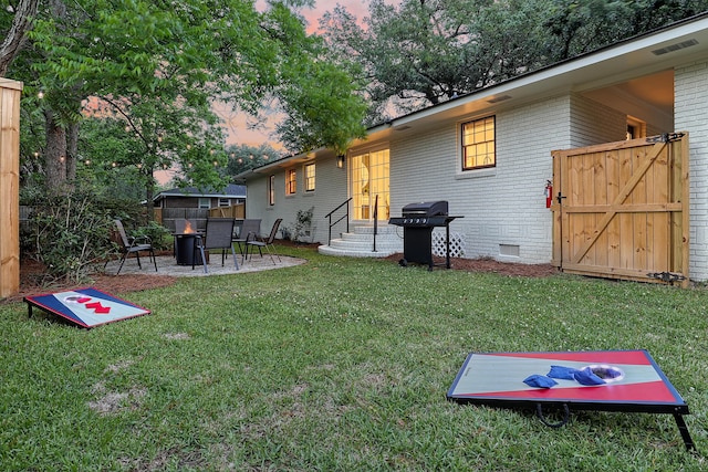 view of green lawn with entry steps, a fire pit, and a patio area