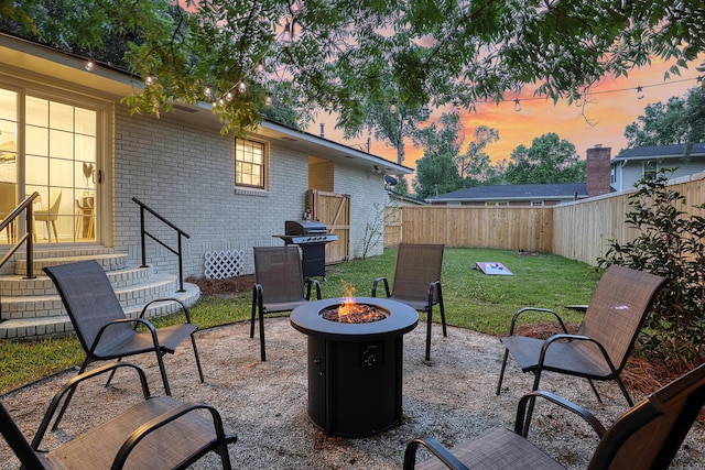 patio terrace at dusk featuring an outdoor fire pit, entry steps, and area for grilling