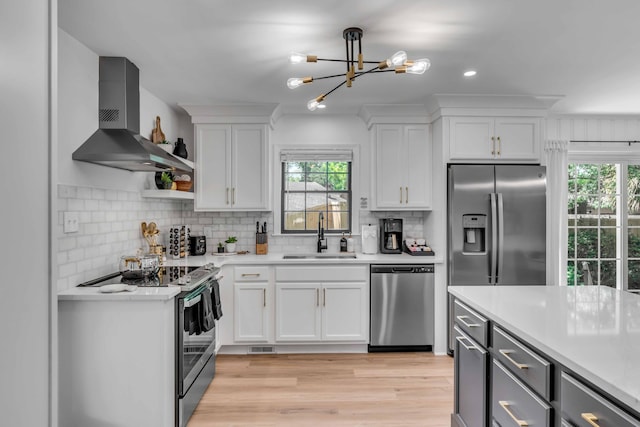 kitchen featuring stainless steel appliances, a sink, wall chimney range hood, plenty of natural light, and recessed lighting