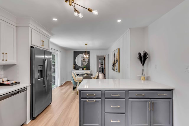 kitchen with appliances with stainless steel finishes, light countertops, light wood-style floors, white cabinets, and recessed lighting