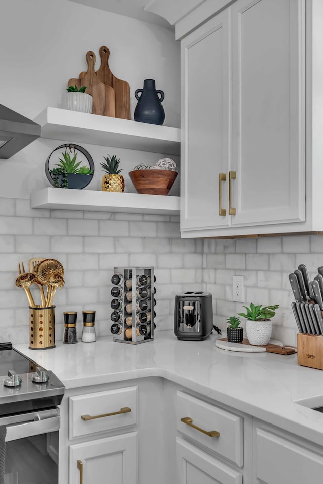 kitchen with open shelves, white cabinetry, decorative backsplash, stainless steel electric range, and light stone counters