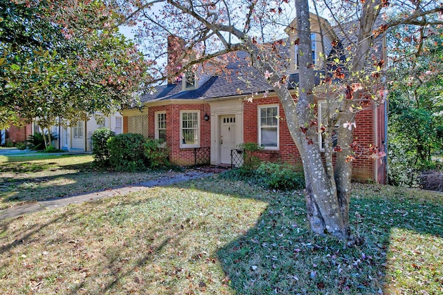 view of front of house with brick siding, a shingled roof, and a front yard