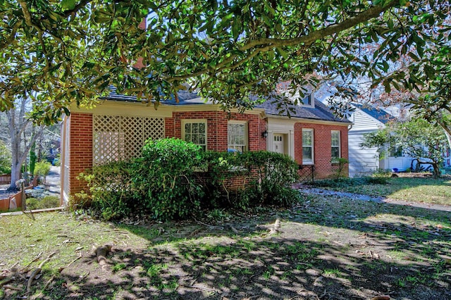 view of front of home featuring brick siding and roof with shingles