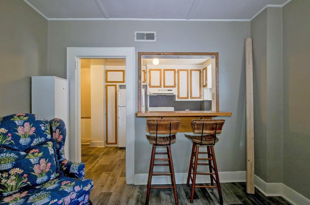 interior space featuring visible vents, baseboards, wood finished floors, and crown molding