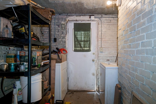 laundry room with washer / clothes dryer, brick wall, and laundry area