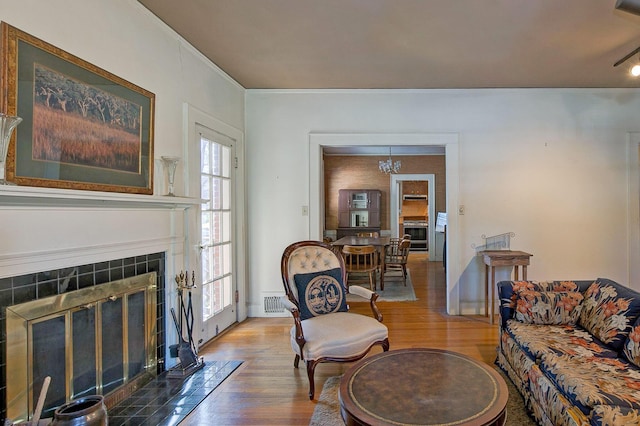 living room with visible vents, plenty of natural light, wood finished floors, and a tile fireplace