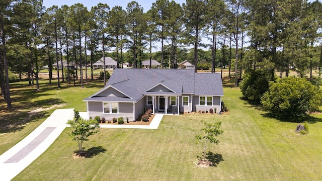 409 Pine Lake Ct, Manning, SC 29102 - view of front facade with concrete driveway, a front yard, a shingled roof, a porch, and view of wooded area