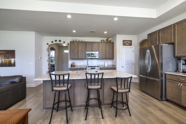 409 Pine Lake Ct, Manning, SC 29102 - kitchen featuring stainless steel appliances, arched walkways, light wood finished floors, baseboards, and recessed lighting