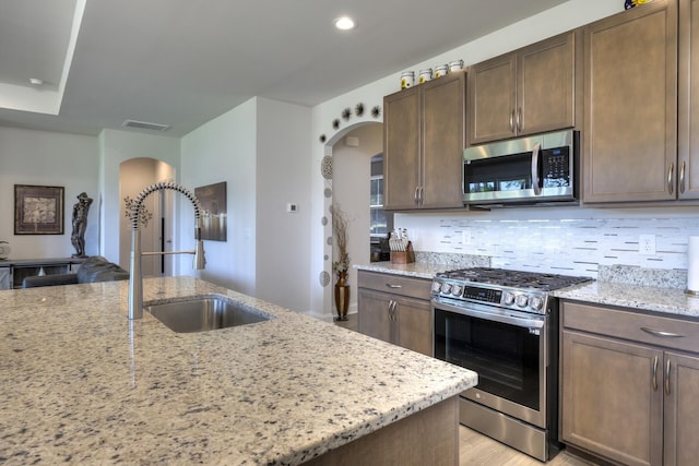 409 Pine Lake Ct, Manning, SC 29102 - kitchen with arched walkways, stainless steel appliances, a sink, light stone counters, and recessed lighting
