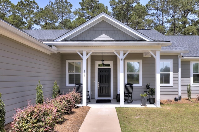 409 Pine Lake Ct, Manning, SC 29102 - view of exterior entry featuring roof with shingles, a porch, and a lawn
