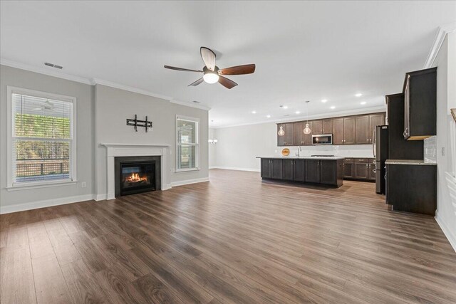 unfurnished living room with crown molding, ceiling fan, and dark hardwood / wood-style floors