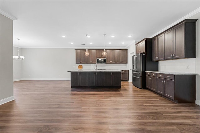 kitchen with dark hardwood / wood-style flooring, pendant lighting, dark brown cabinets, appliances with stainless steel finishes, and ornamental molding