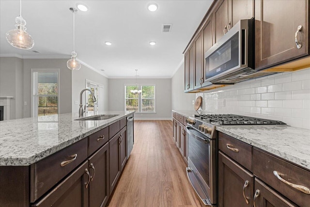 kitchen featuring pendant lighting, a kitchen island with sink, sink, light hardwood / wood-style floors, and stainless steel appliances