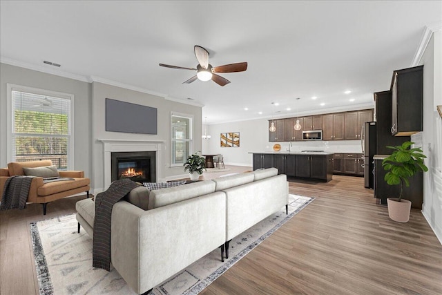 living room with light hardwood / wood-style floors, ceiling fan, and ornamental molding