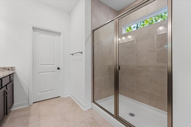 bathroom with a shower with door, vanity, and tile patterned flooring