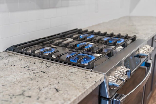 details featuring decorative backsplash and stainless steel gas range