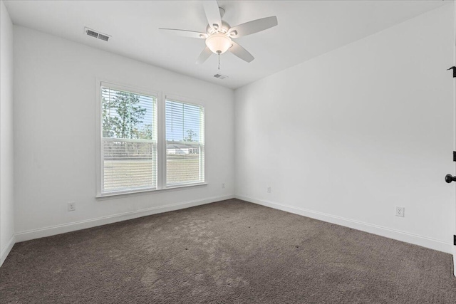 spare room featuring ceiling fan and dark carpet